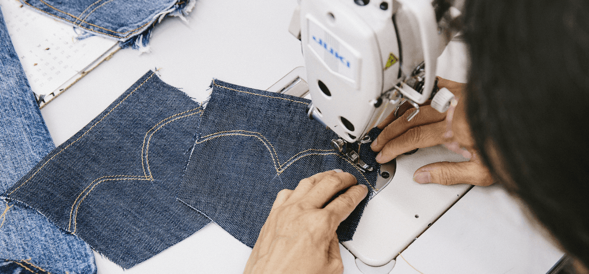 A woman sewing jeans 